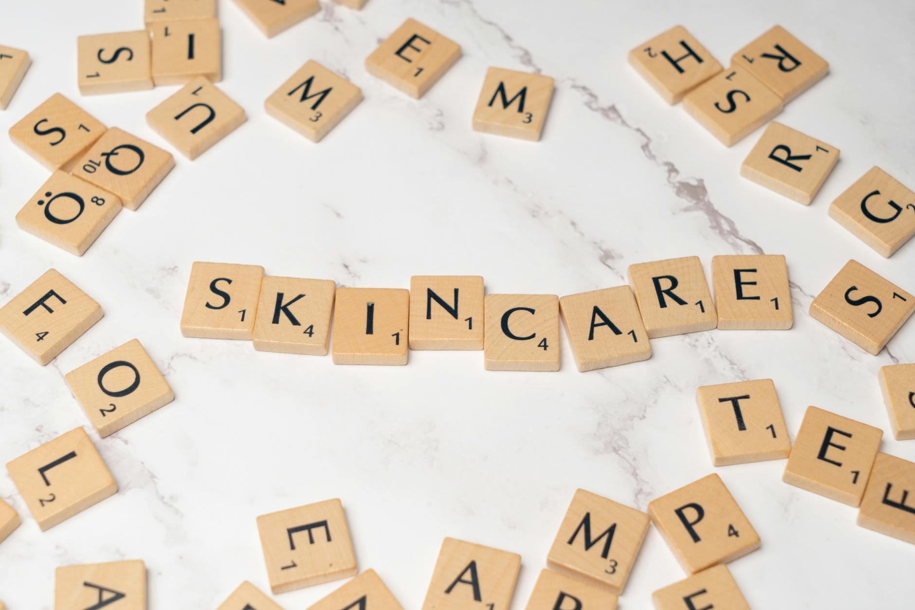 Drewniane kafelki z napisem skincare ułożone na jasnym, marmurowym tle