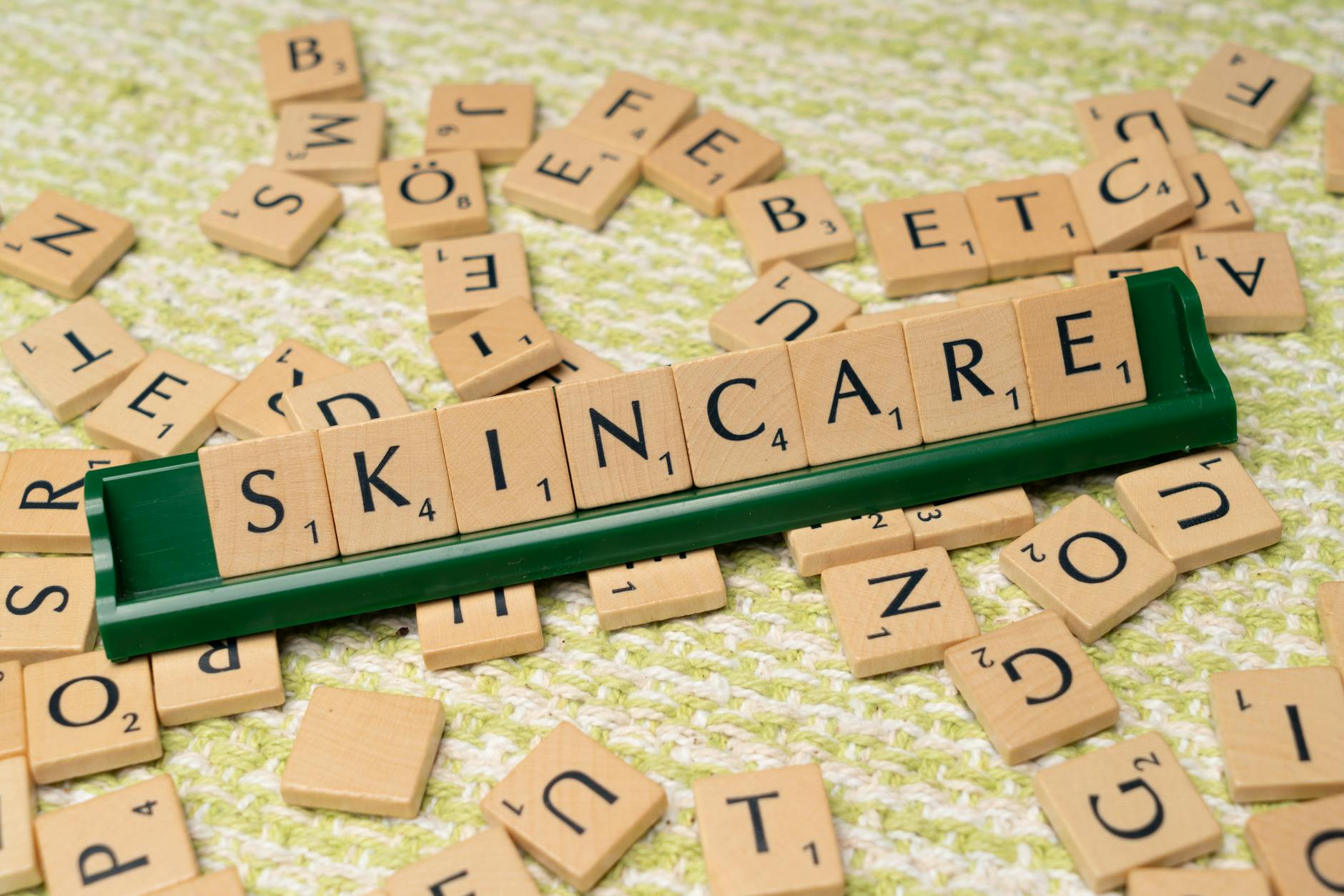 Kafelki Scrabble układające się w napis skincare na zielonym tle