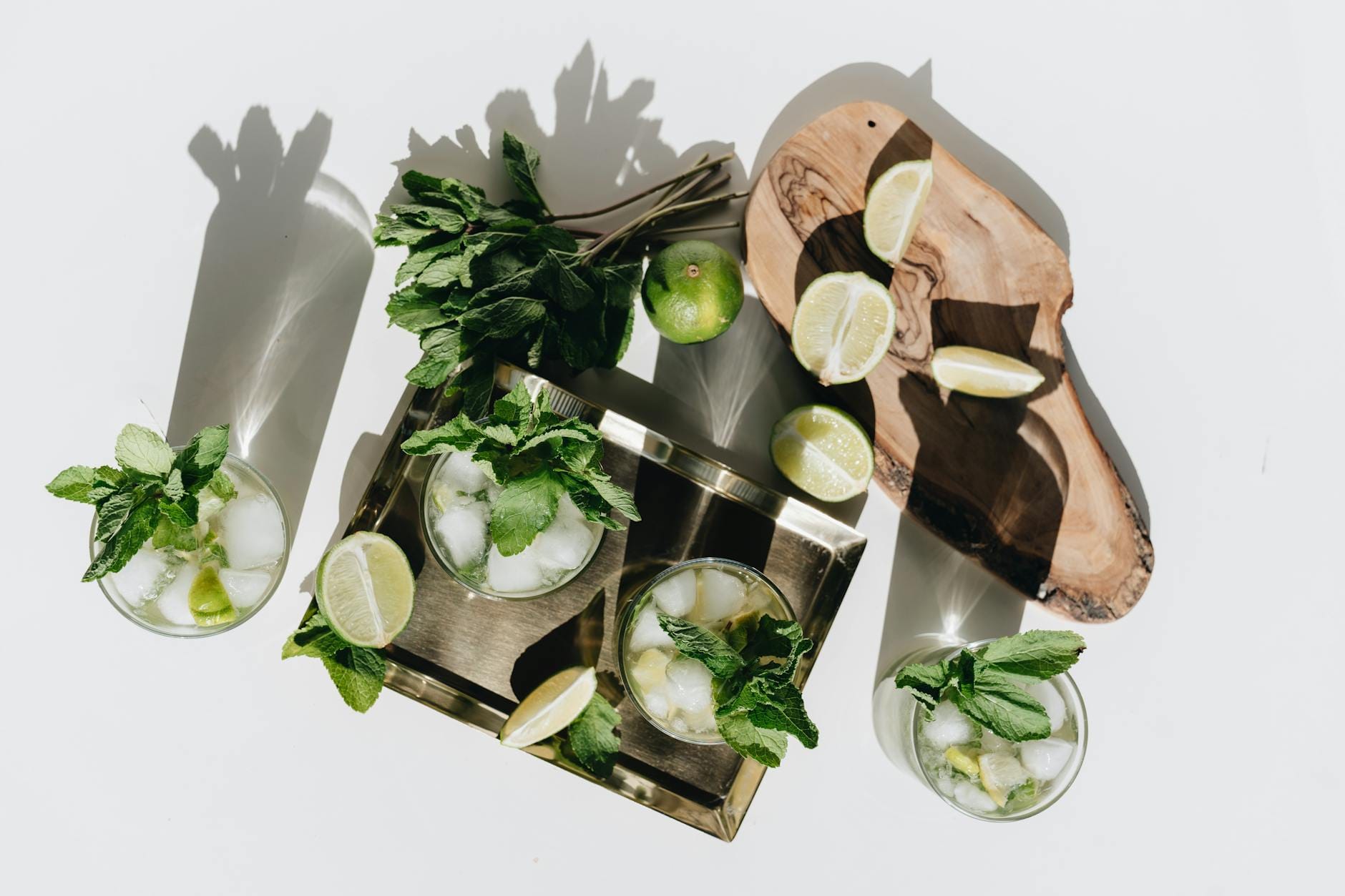 Proste drinki w domu: przewodnik po podstawowych alkoholach, likierach i dodatkach Świeże drinki mojito z limonką i miętą na metalowej tacy