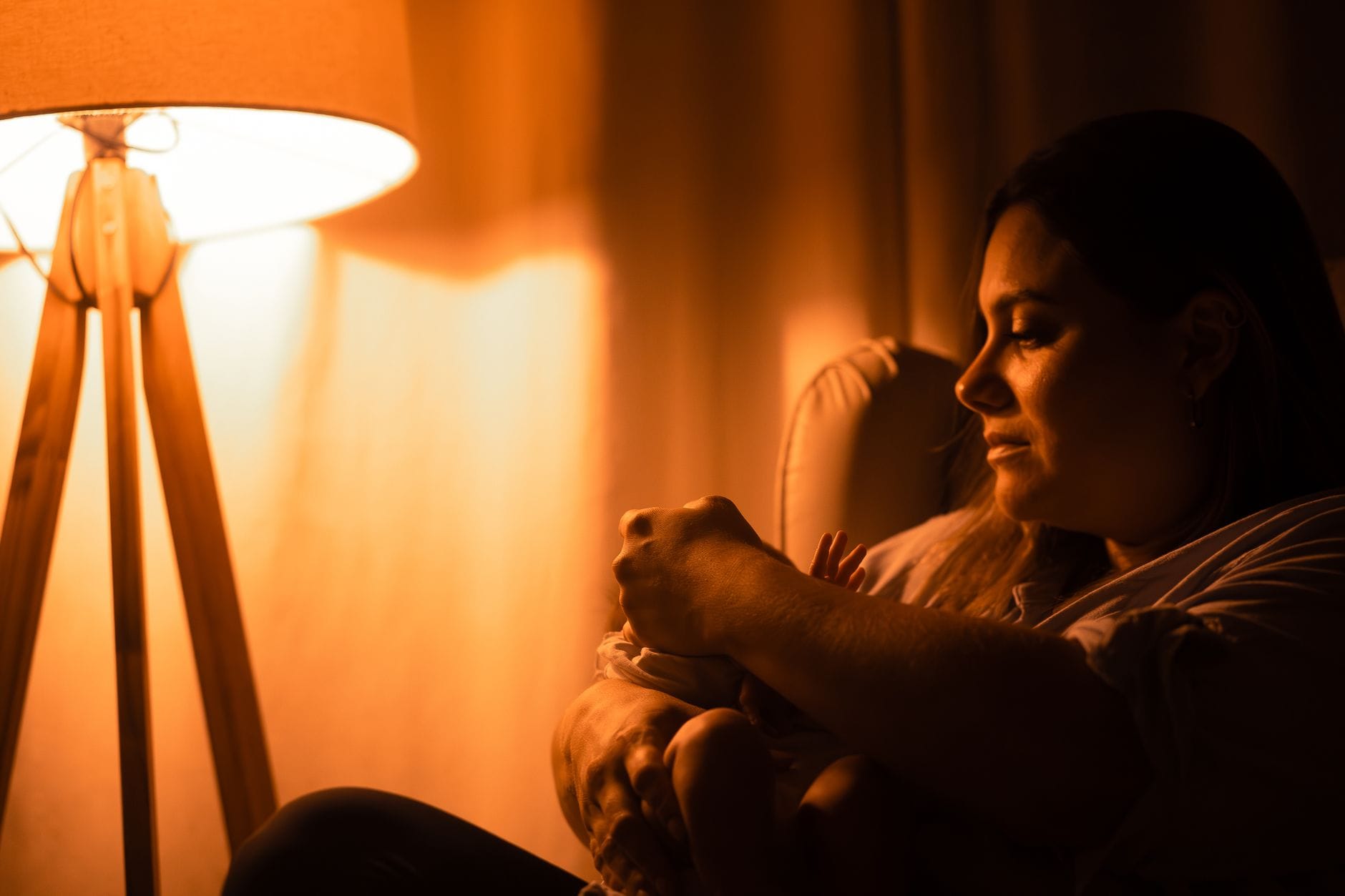 Mama tuląca niemowlę w ciepłym świetle lampki nocnej